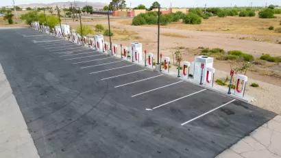 Vacant Tesla charging station in asphalt parking lot next to Interstate 10 in Arizona.