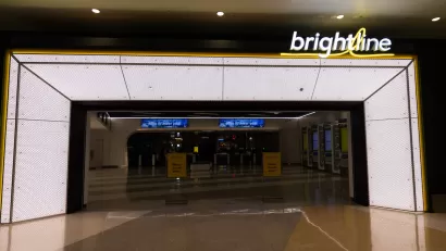 Empty, darkened corridor in transit station before opening with Brightline logo in lights on one side