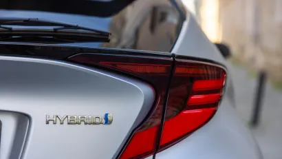 Close-up of Hybrid logo on back of silver Toyota sedan.