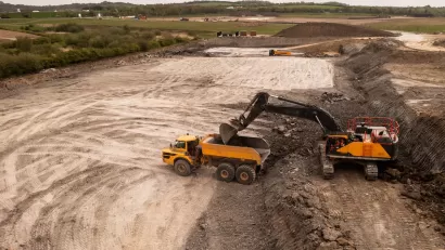 Aerial view of brownfield area with digger loading a dump truck.