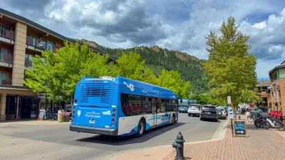 Blue public transit bus on street with mountains in background in Aspen, Colorado.