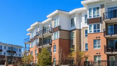 Four-story modern apartment complex with white stucco and red brick.
