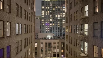 View from between tall white brick buildings in evening in downtown Los Angeles with modern office building across street.