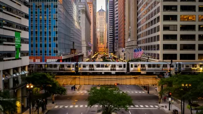 A view straight down LaSalle Street, lined by high-rise buildings with an El line running horizontally over the street.