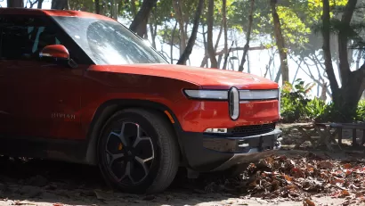 Red Rivian electric truck on forested beach in the Dominican Republic.