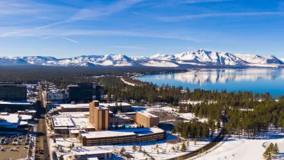Aerial view of snowy town of Stateline, Nevada on shore of Lake tahoe with mountains in background.