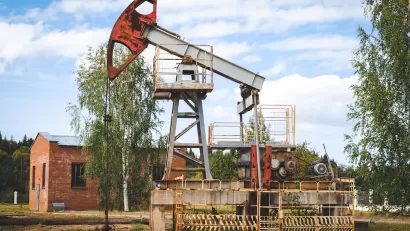 Old oil well with red brick building in the background.