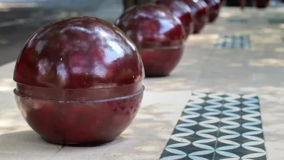 Red spherical bollards lining city sidewalk.
