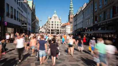 Blurred pedestrians on busy walkable street in Copenhagen, Denmark with old buildings in background