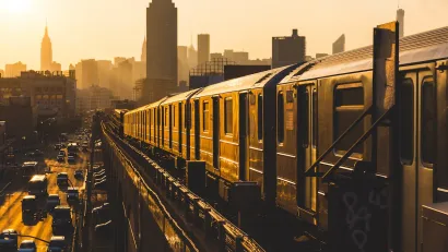 New York City subway train on elevated track in yellow light.
