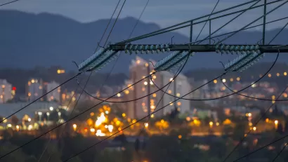 Close-up of power lines with urban night scene blurred in background.