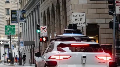 Close-up of back of white self-driving Waymo car on San Francisco street.