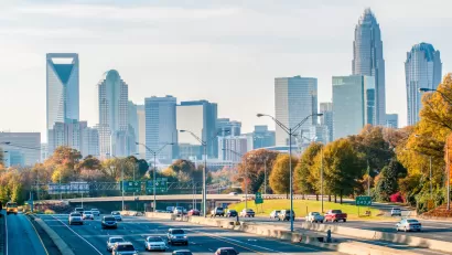 View of cars on freeway with Charlotte, North Carolina skyline in background.