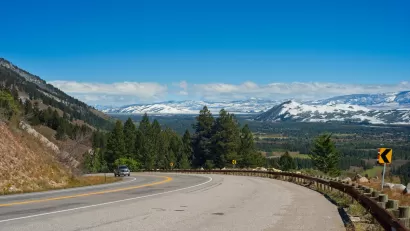 Curve in mountain highway along Teton Pass with snowy Wyoming mountains in background.