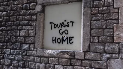 Spray painted words "Tourist Go Home" on wall in Barcelona illustrate locals' frustration with overtourism.