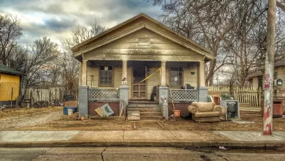 Old single-story home with porch in run-down condition