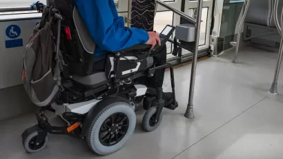 Man in wheelchair in designated area on public bus.