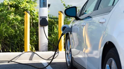 White electric car being charged in parking lot.
