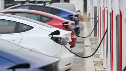 Close-up of four Tesla sedans parked and plugged in at charging station.
