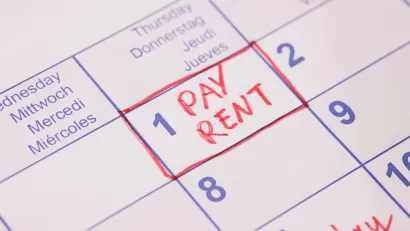 Close-up of 'Pay rent' note in red marker on day 1 of monthly calendar.