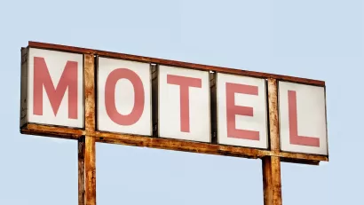 Close-up of faded old MOTEL sign with red letters on white placards against blue sky.