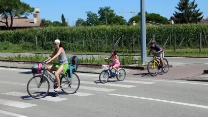 Woman and two children riding bikes across a striped crosswalk.