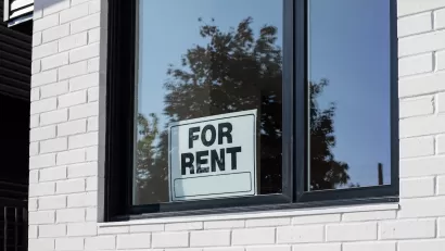 For Rent sign in window on white tiled wall.