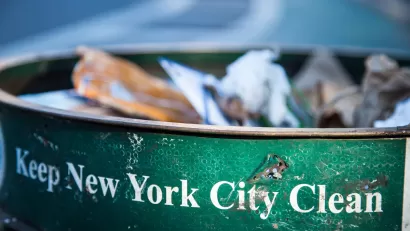 Close-up of green New York City public trash can with white text "Keep New York City Clean."
