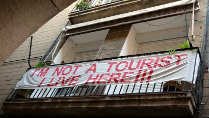 Banner reading "I'm not a tourist - I live here!!!" hung on balcony in Barcelona, Spain.