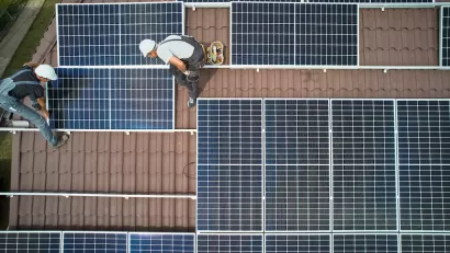 Bird's eye view of workers installing solar panels on rooftop.