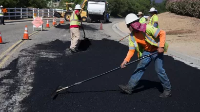Workers putting down asphalt on road.