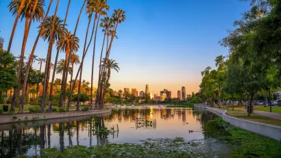 View of downtown Los Angeles at dusk with Echo Park lake and palm trees in foreground.