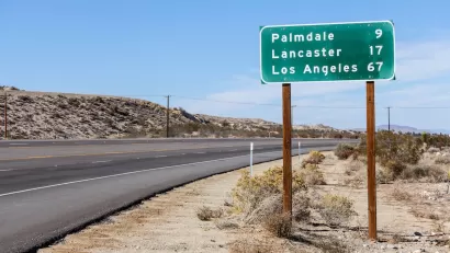 Green highway sign with white text with distances for Palmdale, Lancaster, and Los Angeles, California.