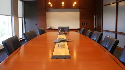 Large brown wood conference table surrounded by black leather chairs.