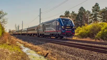 An Amtrak passenger train is shown on a spring day, rolling through a rural area in Missouri.