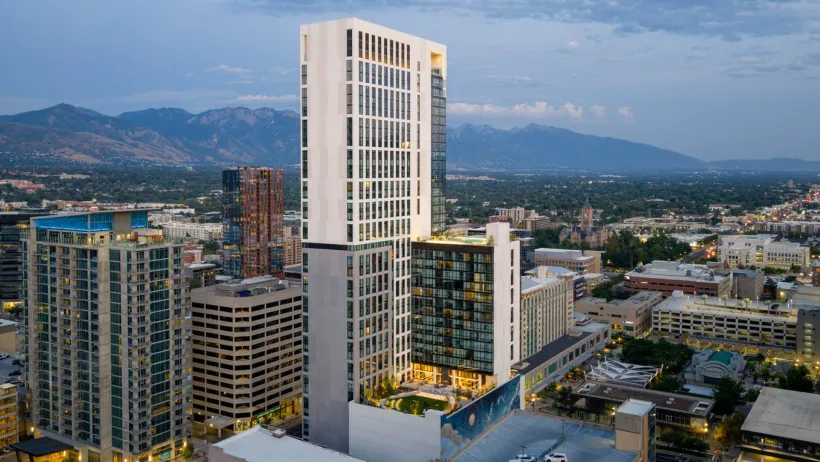 High-rise building with white top floors in downtown Salt Lake City, Utah with mountains in background.