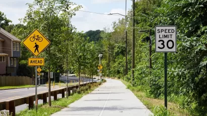 Paved Atlanta Beltline trail segment next to street with bike and pedestrian crossing sign and 30 mph speed limit sign.