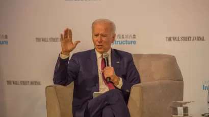 Joe Biden sits in a chair holding a microphone in front of a screen that reads Wall Street Journal and Infrastructure