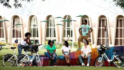 Promotional photo of diverse group of young people sitting on colorful bench with their Bublr bike share e-bikes parked in front of them.