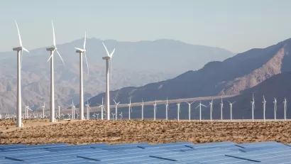 Wind turbines and solar panels against a backdrop of mountains in the Mojave Desert near Palm Springs, California