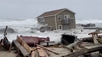 A house has been swept into the Atlantic Ocean by high tides, leaving ruins in onshore as the house appears half submerged by water,