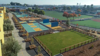 Aerial view of schoolyard in Oakland, California with newly planted trees, sports courts, and playground equipment.