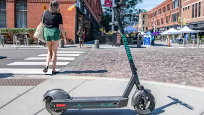 An electric scooter blocks the sidewalk near a street festival in Chicago's West Loop.