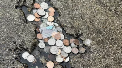 Rat shaped indentation on pavement, filled with coins