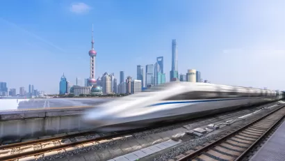 A high-speed rail is blurred as it passes a modern skyline in China.