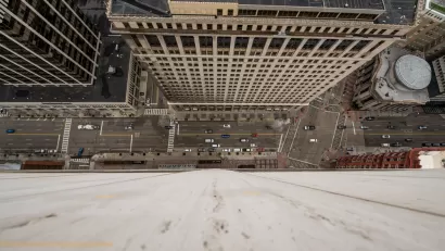 A busy urban street is seen from the vantage point offered by looking straight down from the top of a high-rise.