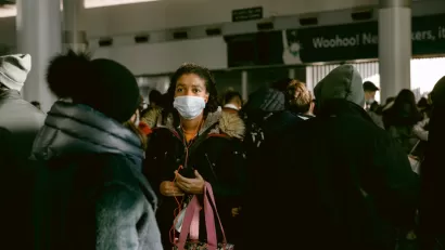 A woman wears a mask during the Covid-19 pandemic in a large crowd at a transit station in New York City.