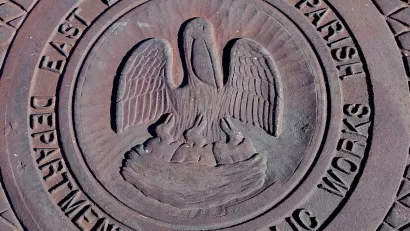 Close-up of metal manhole cover with pelican logo and 'East Baton Rouge Parish Department of Public Works.'