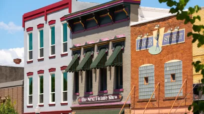 A row of multistory, brick buildings in a small U.S. city, with retail uses on the ground floor and apartments above.