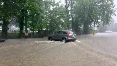 A sports utility vehicle drives throw brown floodwaters that have inundated the entire area depicted in the picture.